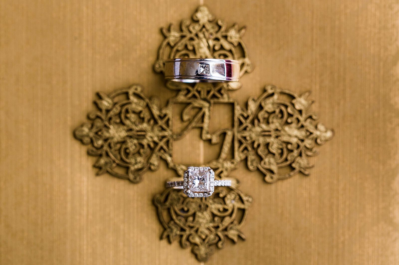 Wedding rings placed on elegant calligraphy invitation suite with floral details