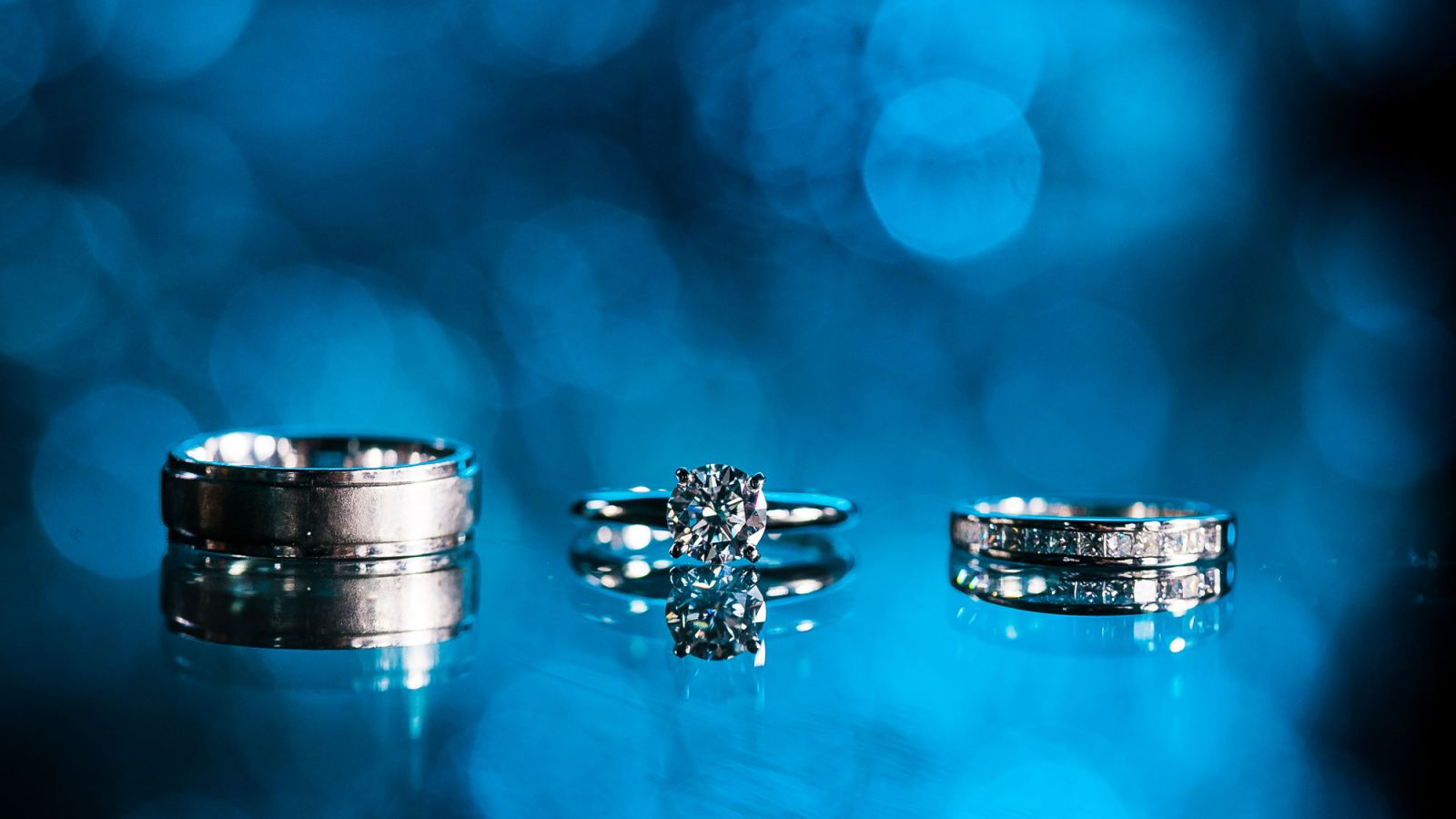Wedding rings reflected on polished black surface creating mirror symmetry effect