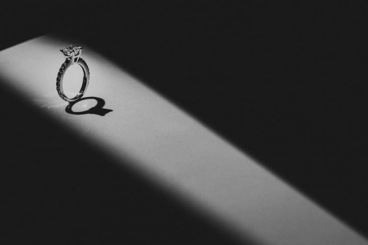 Wedding rings illuminated by dramatic light pattern creating geometric shadows