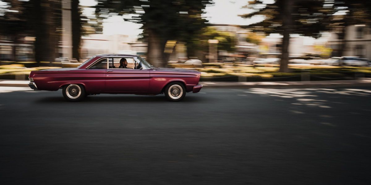 Panning photography example showing a car with a sharp subject and dynamic horizontally blurred background demonstrating the technique at moderate shutter speed